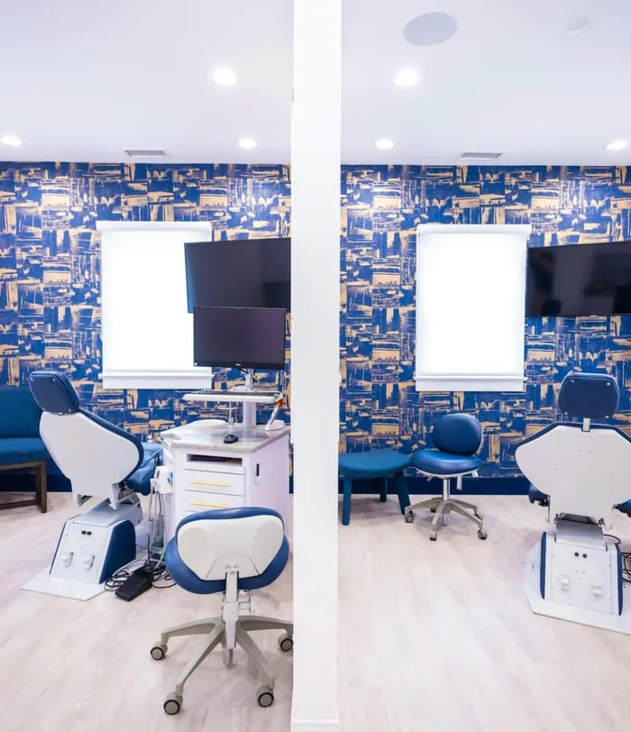 Two treatment chairs in a room papered in navy and gold, each with its own screens.